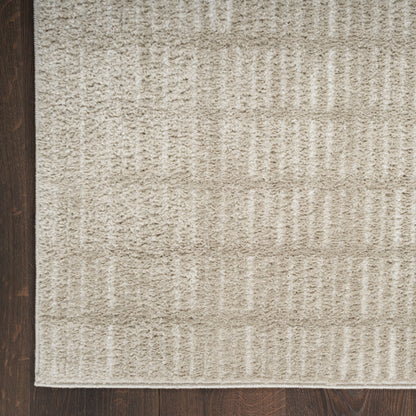 Beige textured area rug with a geometric block pattern on a dark wood floor.