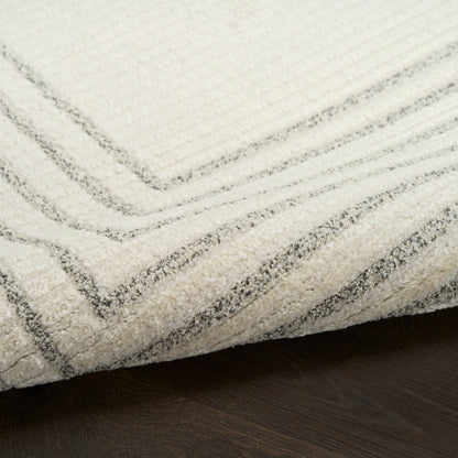 Cream rug with subtle gray chevron pattern, plush pile, folded edge on dark wood floor; modern cozy area rug.
