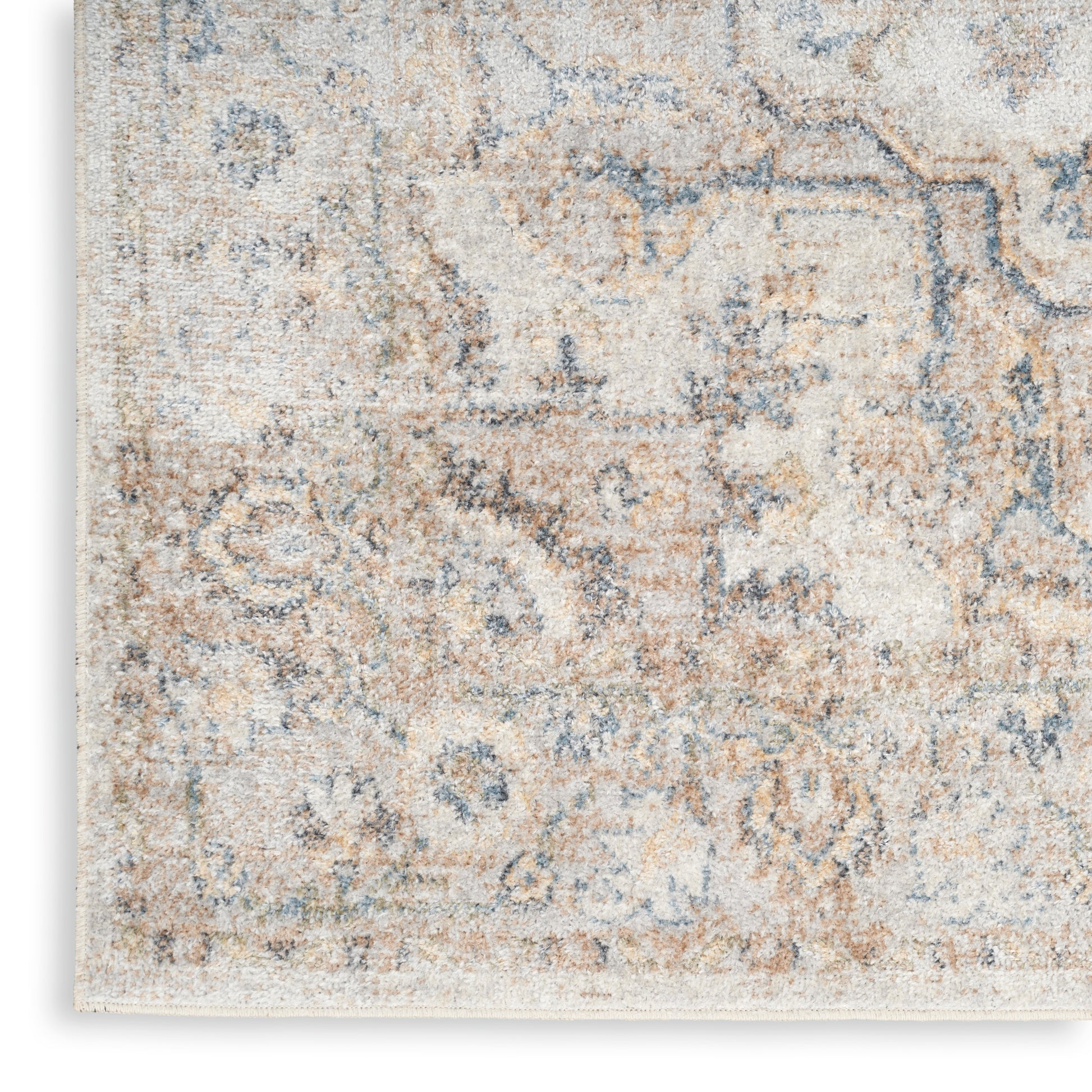 Close-up of a distressed beige-blue area rug with a muted floral pattern and soft woven texture.