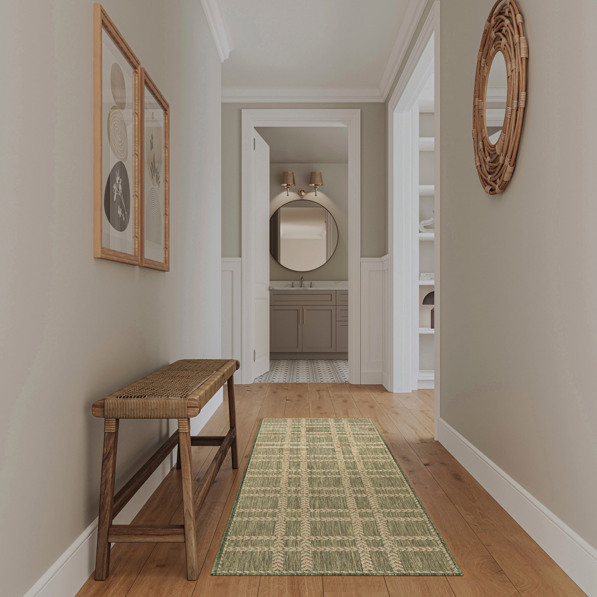 Neutral hallway with gray walls, white wainscoting, wooden bench, green runner, round wicker mirror; leads to bathroom.