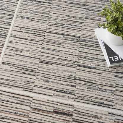Beige and gray woven area rug with raised linear stripe pattern; white pot with green succulent sits on stacked magazines.