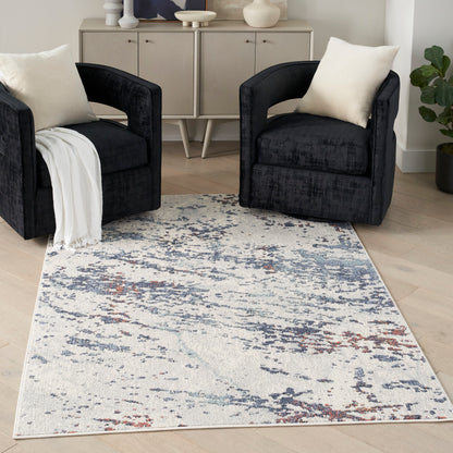 Two black velvet armchairs with cream cushions flank a light abstract blue-gray rug in a modern living room with a sideboard.