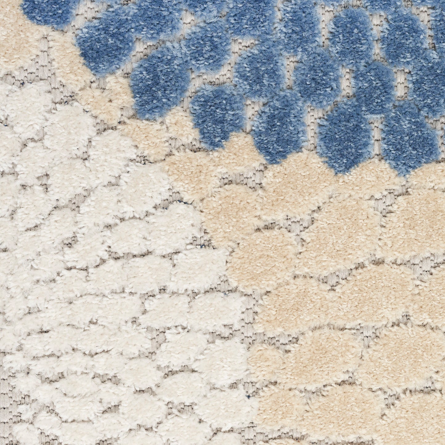 Soft boucle shag rug in cream and beige with blue tufted clusters forming an abstract pattern.