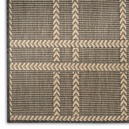 Rectangular jute rug in charcoal and natural beige with chevron grid geometric pattern; flat-weave, tribal-inspired, textured.