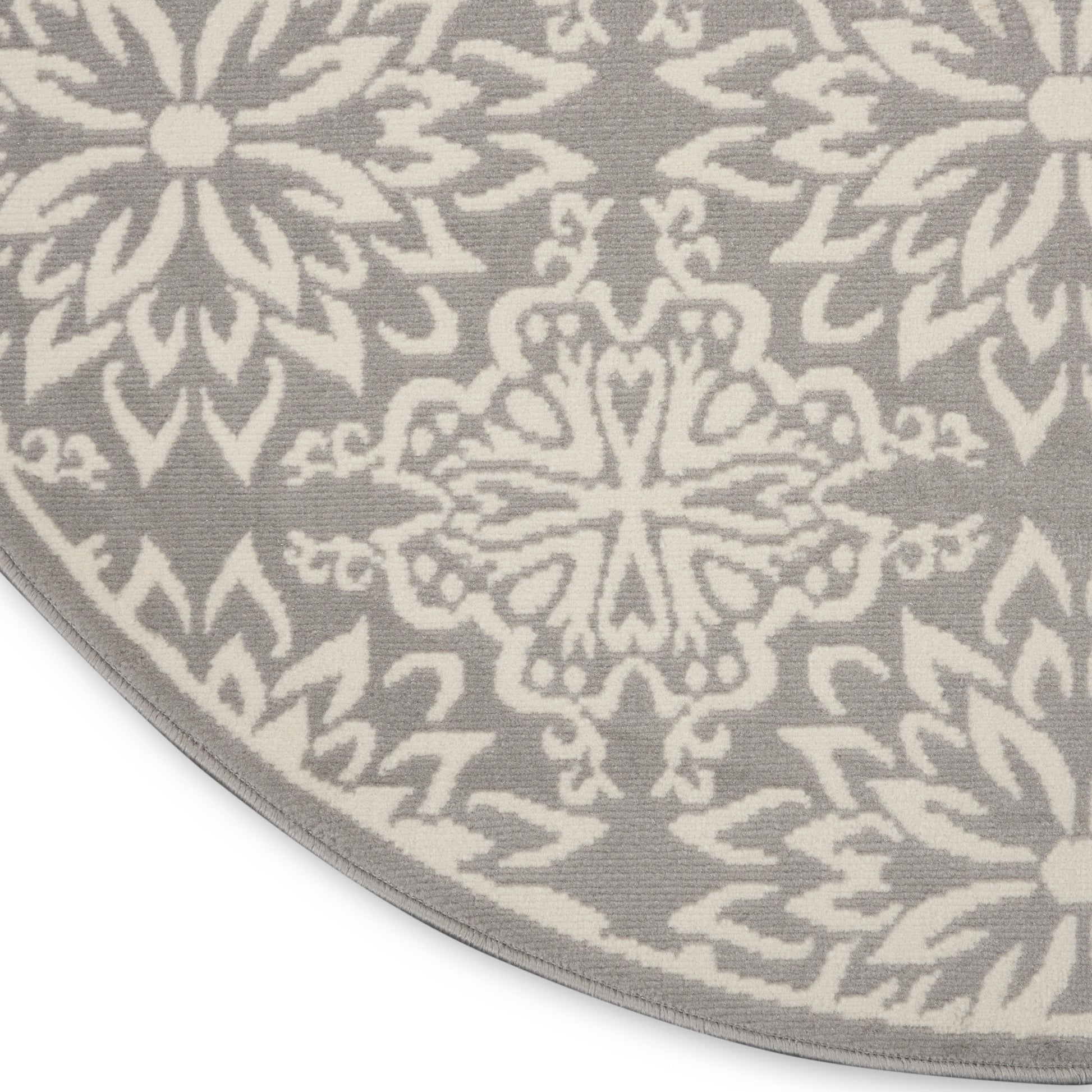 Round grey rug with a white mandala floral pattern & a light border along the edge.