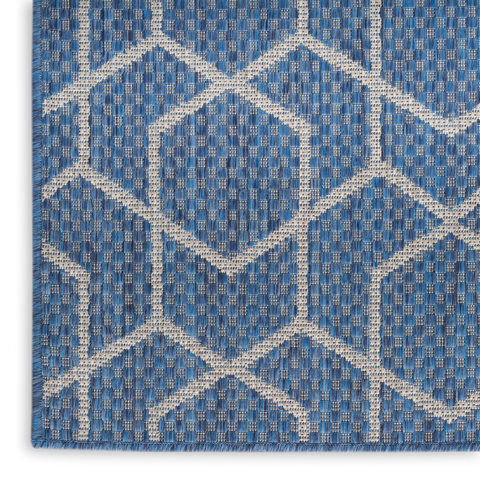 Blue woven rug with white geometric diamond trellis pattern; textured textile for living room.