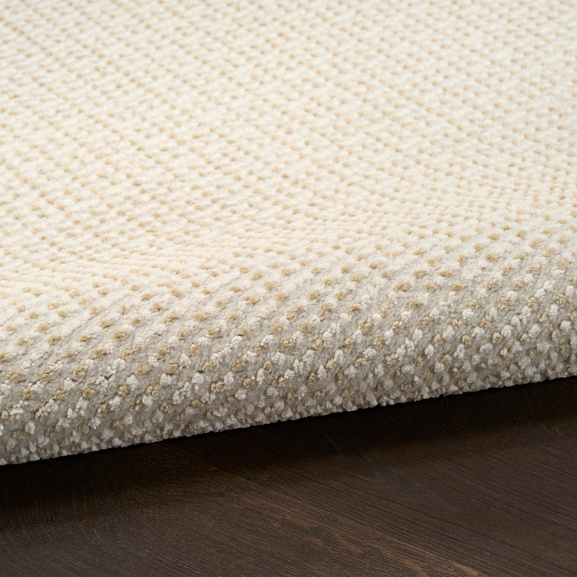 Beige textured boucle rug with low-pile, dotted pattern on dark wooden floor.