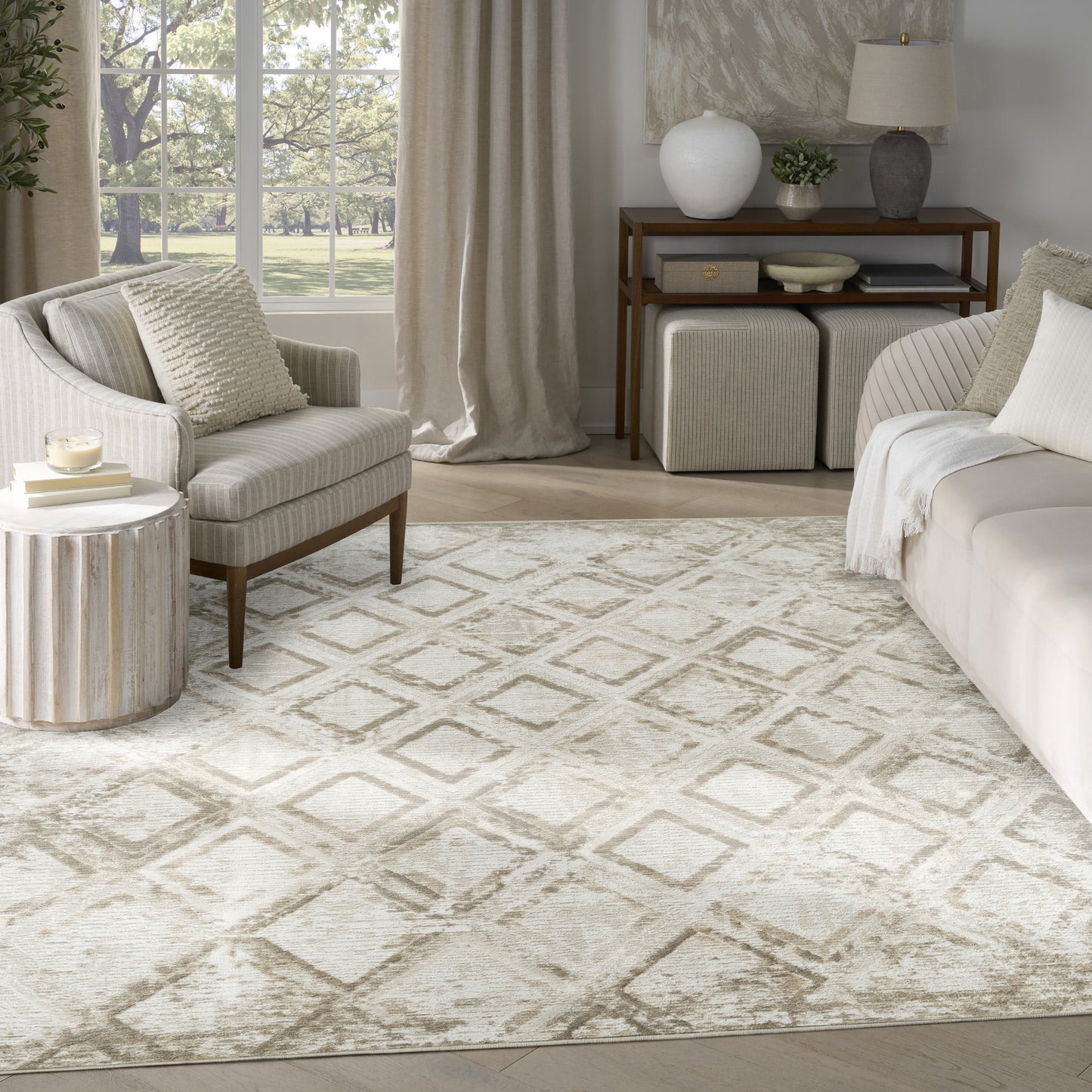 Neutral living room with ivory diamond-pattern rug, beige sofa and armchair, wood side table, and decorative console.