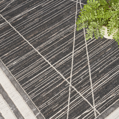 Charcoal striped rug with cream geometric lines, near a potted fern; modern, low-pile floor accent.