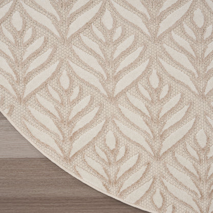 Beige area rug with cream leaf/fern pattern and curved edge on light wood floor.