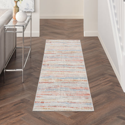 Long distressed multicolor runner rug with cream, blue and orange stripes along hallway beside a glass-topped console table.