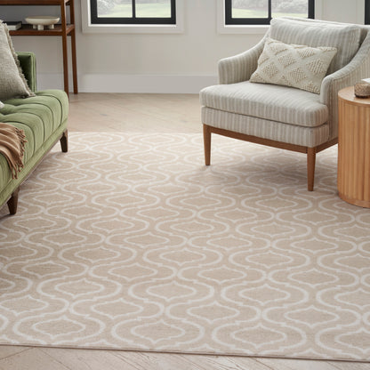 Beige area rug with white wavy trellis pattern, living room with green sofa, grey armchair, wooden side table.
