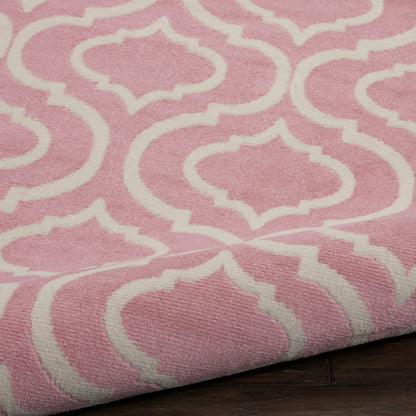 Pink woven round rug with white trellis pattern; folded edge visible on dark wooden floor.