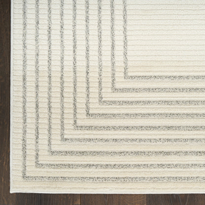 Cream textured area rug with concentric rectangular borders in light gray on dark wood floor.