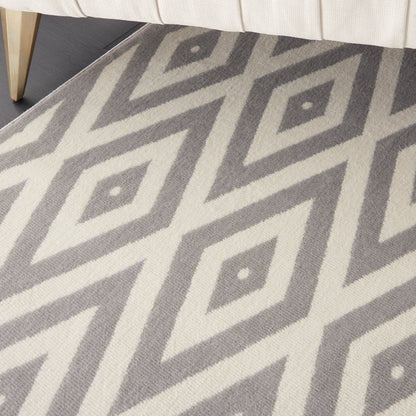 Gray and ivory diamond-pattern rug under a cream sofa, with a light wood furniture leg visible.