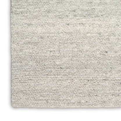 Cream textured wool-blend rug with soft loop pile and gray speckles; rectangular corner visible.