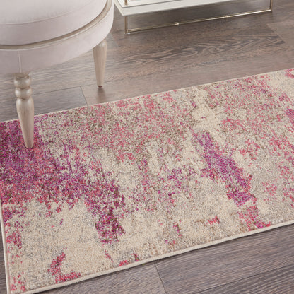 Rectangular area rug with abstract pink and purple splashes on cream, modern design beside beige chair and glass table.