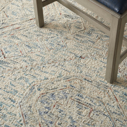 Textured cream area rug with blue and red diamond motifs under a gray wooden coffee table.
