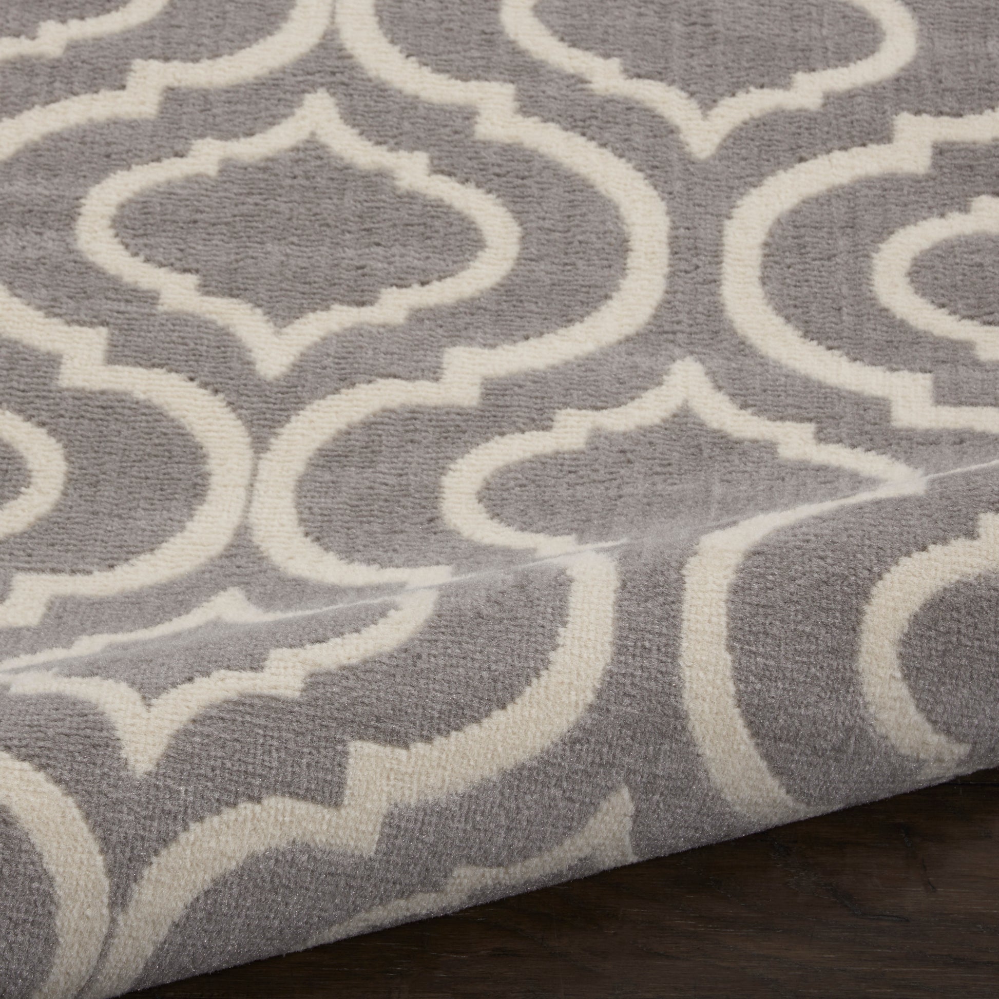 Grey rug with white trellis/quatrefoil pattern; plush woven texture, modern Moroccan-inspired living room decor.