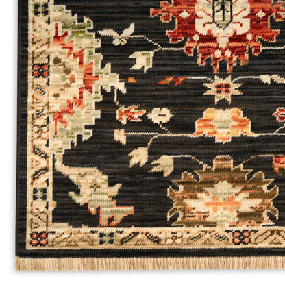 Close-up of an oriental rug: black field with red, ivory, and beige floral motifs; cream border and fringe at edge.