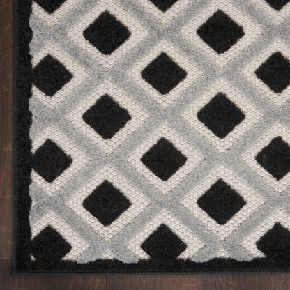 Gray and black diamond lattice runner rug with tufted pile and dark border on wood floor.