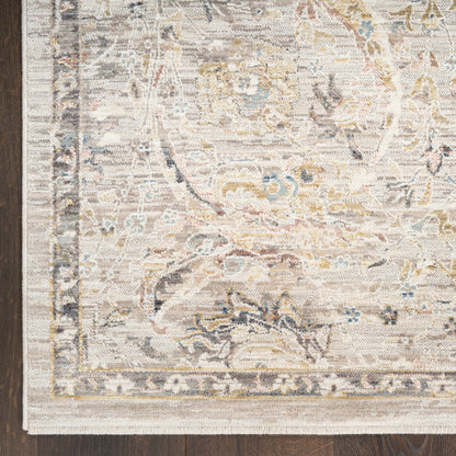 Cream-toned oriental rug with a distressed floral medallion, pale blue and gold accents, fringed edge on dark wood floor.