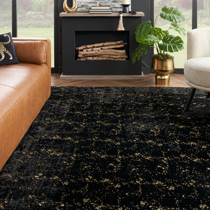 Contemporary living room with black and gold speckled rug, tan leather sofa, beige chair, and black fireplace.