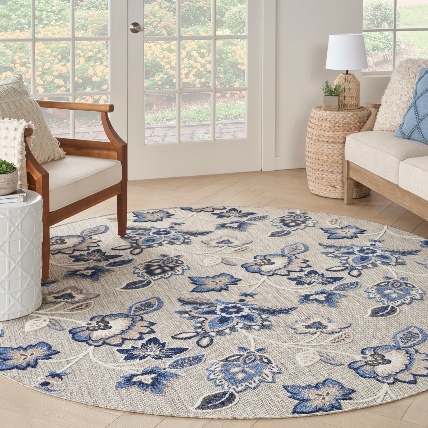 Round floral area rug with blue and navy flowers on a beige background; woven textile, living room decor.