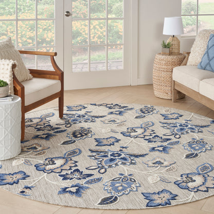 Round floral area rug with blue and navy flowers on a beige background; woven textile, living room decor.