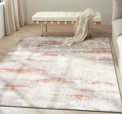 Abstract cream, gray and rust area rug on light hardwood floor beside a white tufted bench with wooden legs.