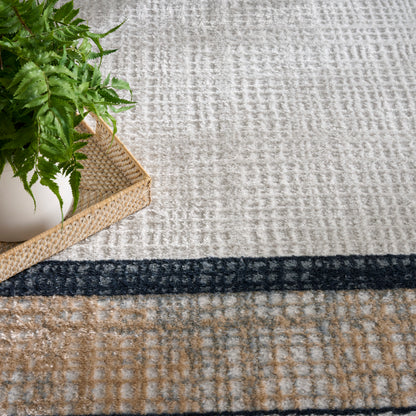 Green fern in a white pot on a woven tray resting on a textured beige rug with navy and tan stripes.
