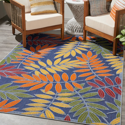Colorful tropical leaf rug with orange, yellow and green leaves on a blue background; pairs with wooden-framed seating.