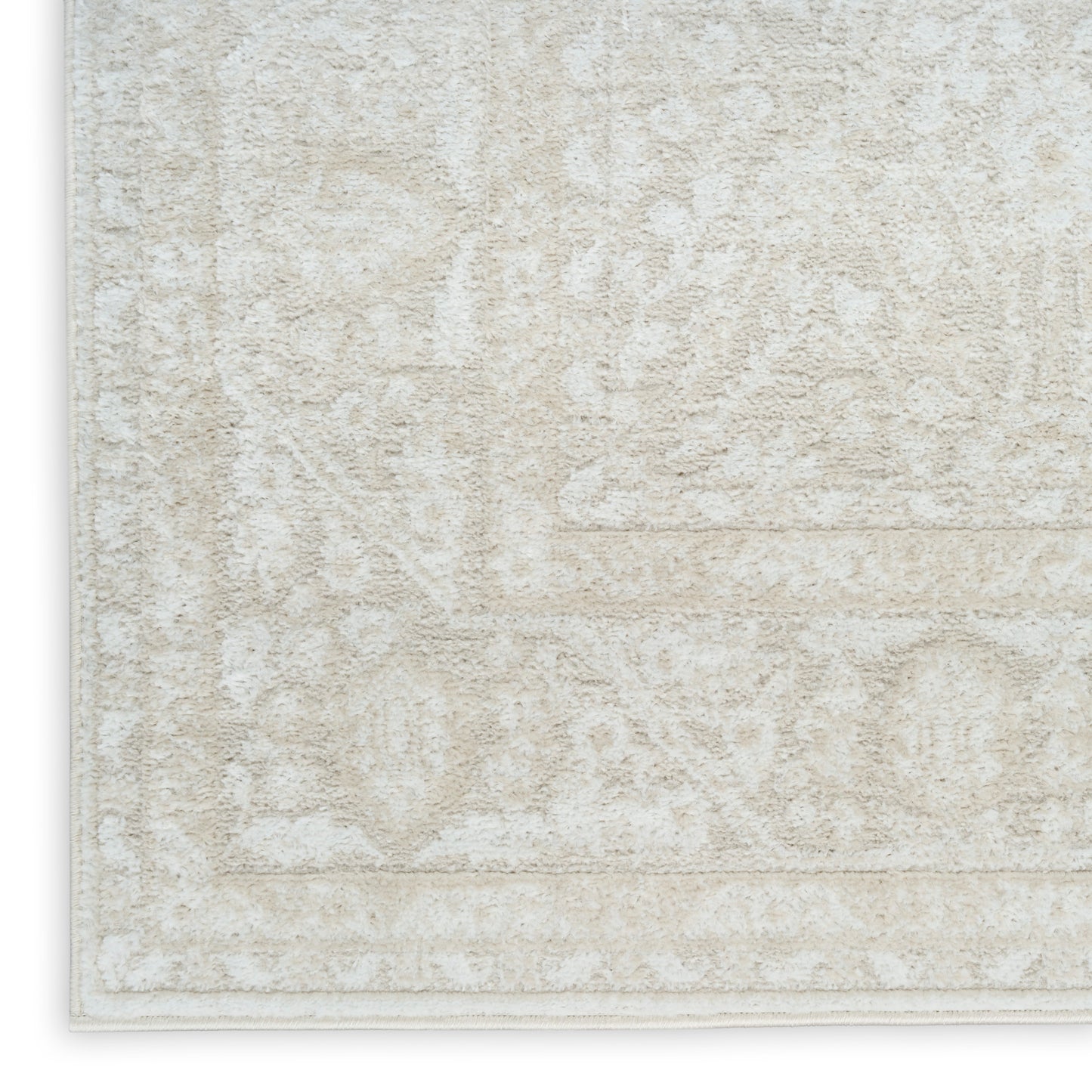 Beige textured area rug with a subtle ivory floral/medallion pattern and light border.