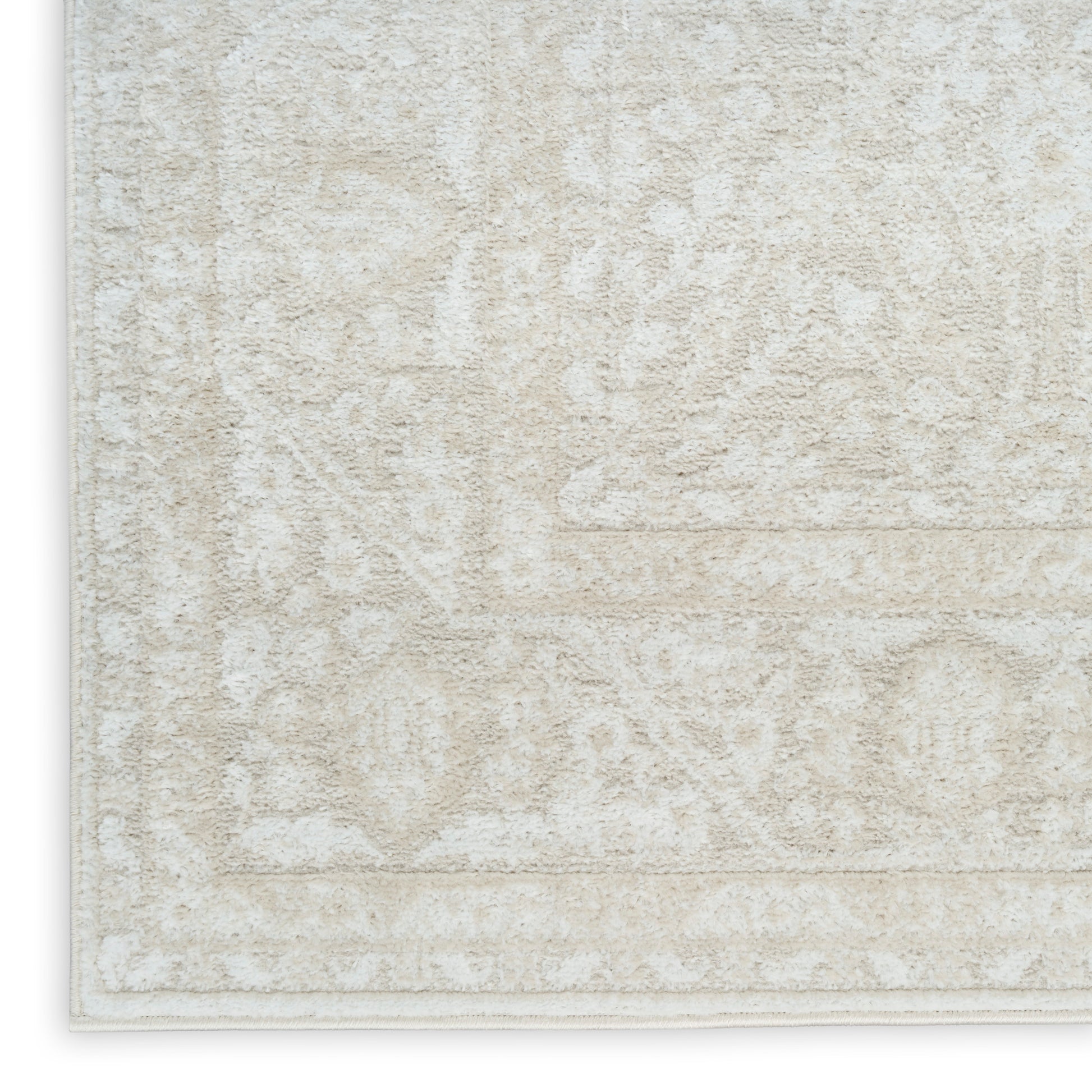 Beige textured area rug with a subtle ivory floral/medallion pattern and light border.