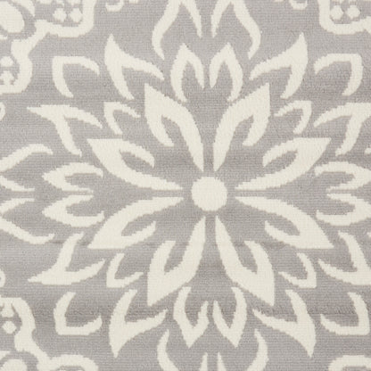 Grey woven fabric with white symmetrical floral damask pattern; radial medallion design for upholstery or decor.