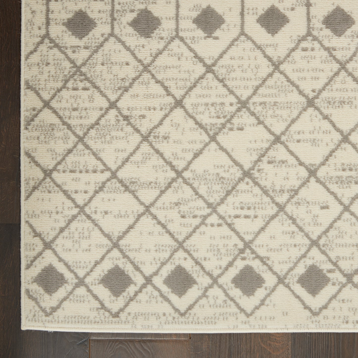 Beige woven rug featuring gray diamond lattice with small diamond accents and fringed edge.