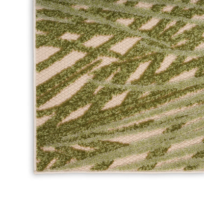 Beige woven rug close-up with olive green abstract leaf pattern, textured surface and bound edge.