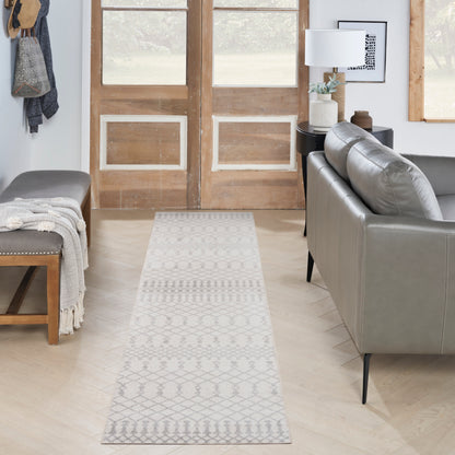 Light gray and white geometric runner rug in a modern living area with a gray sofa and wooden double doors.