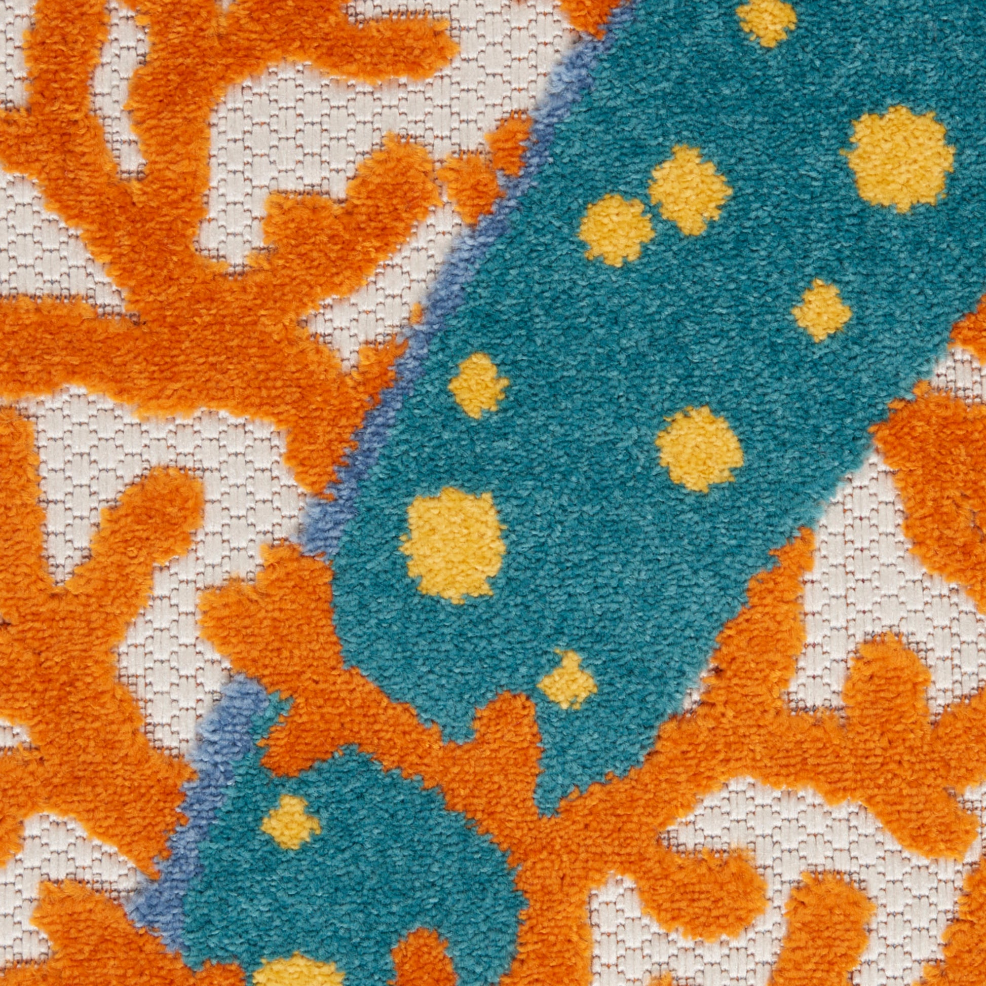 Close-up of a textured rug with a teal stripe dotted in yellow over orange coral-like shapes on a beige background.