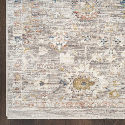 Distressed vintage-style floral area rug in gray-beige with blue, yellow and rust accents; decorative border, corner view.
