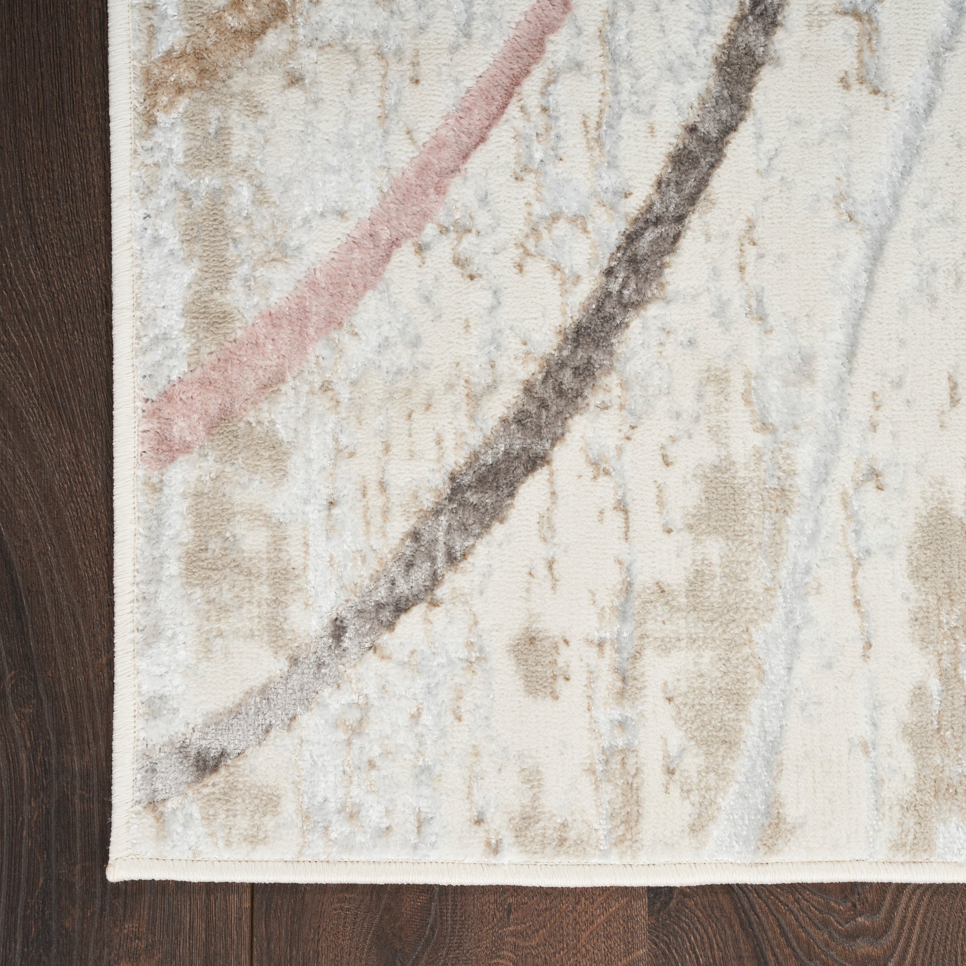 Abstract beige rug with pink and charcoal curved lines on dark wood floor; soft textured weave.