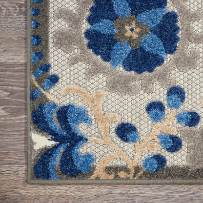 Beige floral area rug with vivid blue flowers and tan stems, bordered edge on wood floor.