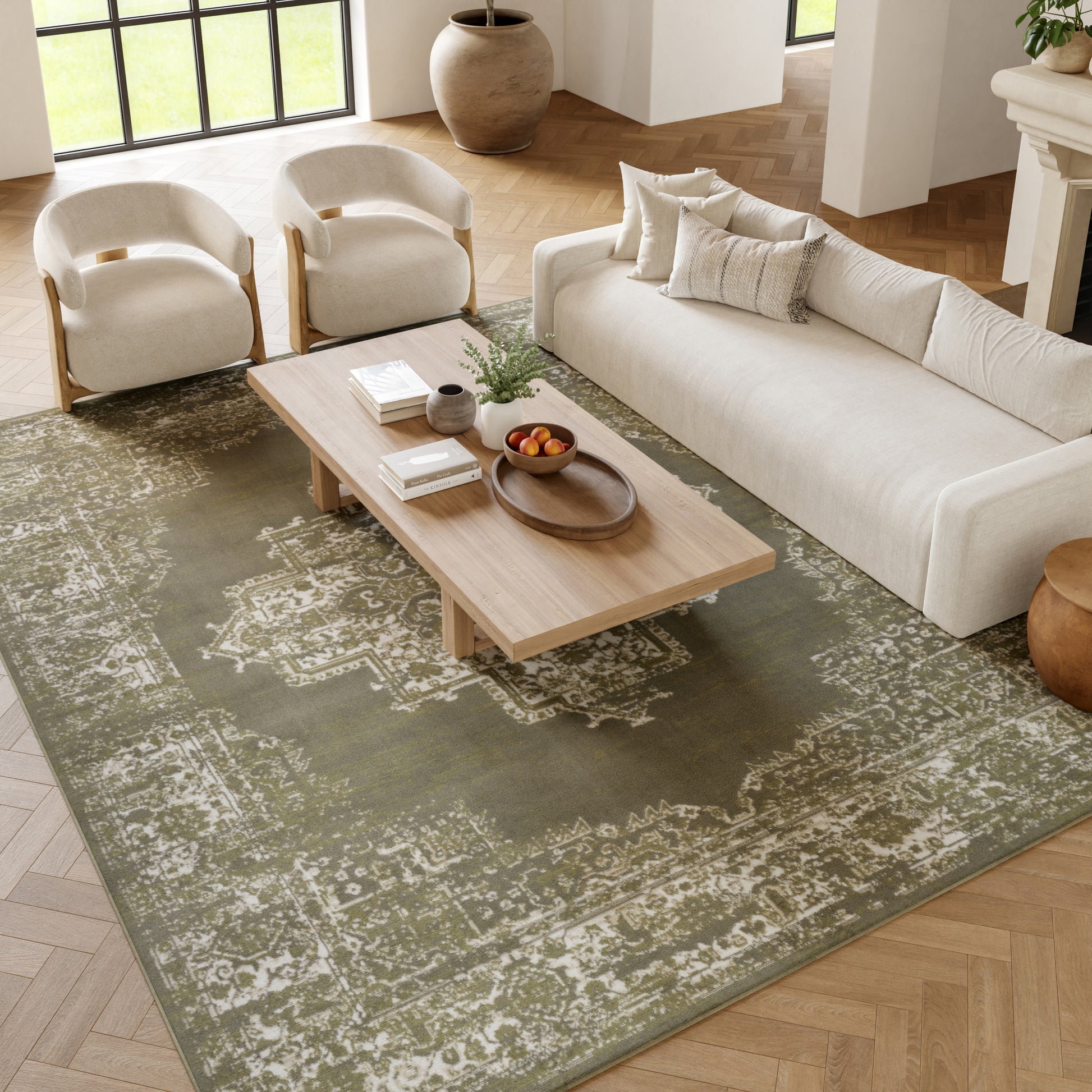 Vintage green distressed oriental rug, 7' x 10', in a living room with a beige upholstered sofa, cream curved-wood chairs and a light wood coffee table.