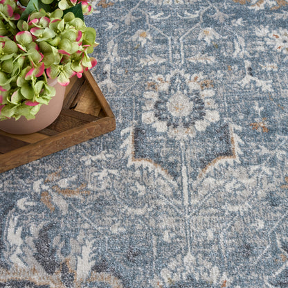 Blue-gray Oriental rug with faded ivory motifs; wooden tray holds a pink pot of green hydrangeas.