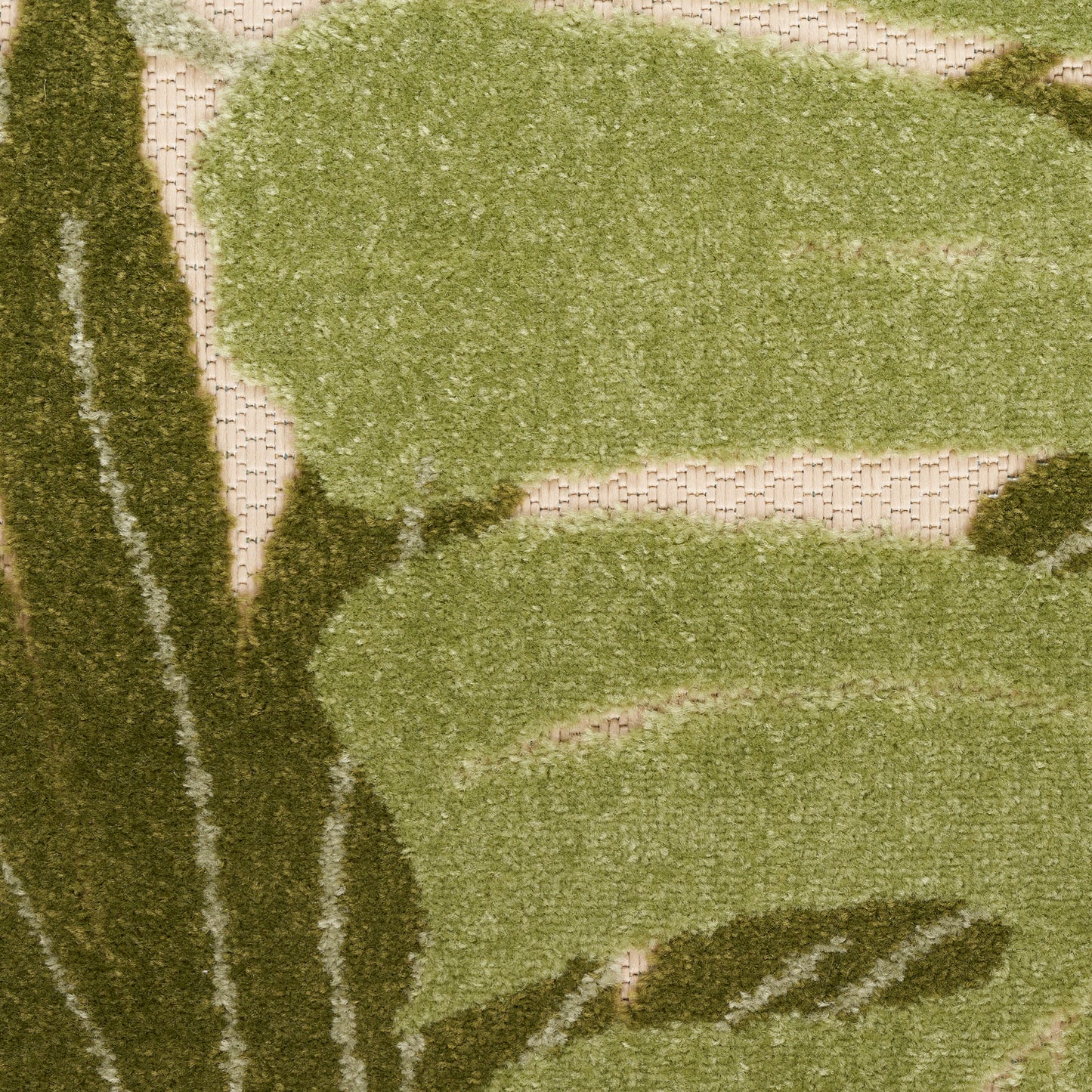 Outdoor rug in olive and sage green with abstract botanical shapes on a beige woven base; textured.