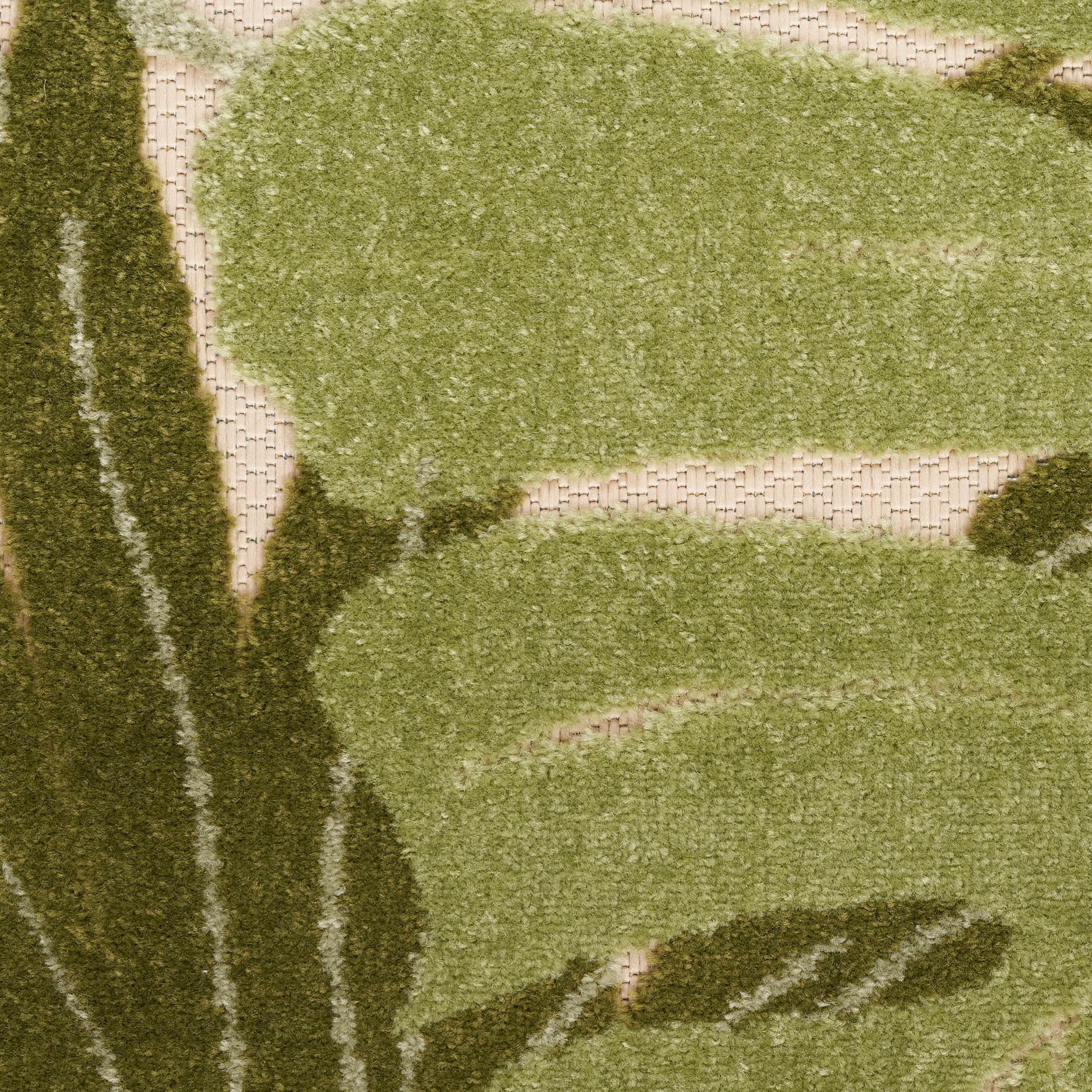 Outdoor rug in olive and sage green with abstract botanical shapes on a beige woven base; textured.