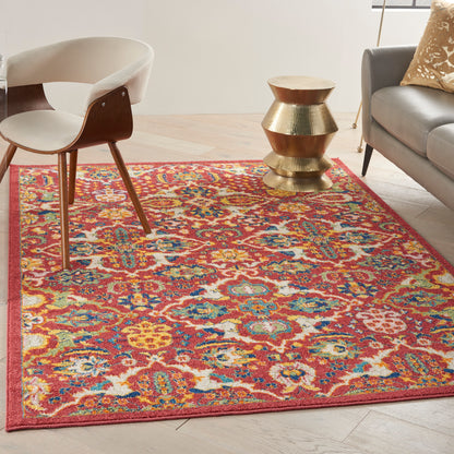 Colorful Bohemian rug in red, orange, blue, and yellow with a mid-century chair and gold stacked side table beside a gray sofa.