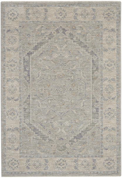 Muted gray-blue oriental rug featuring a central geometric medallion, layered borders, and subtle floral motifs.