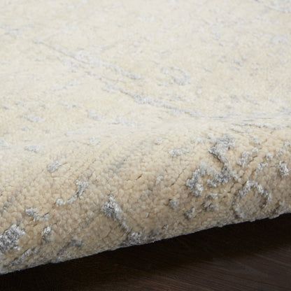 Cream shag rug with pale gray pattern, plush pile and rolled edge on dark wood floor.