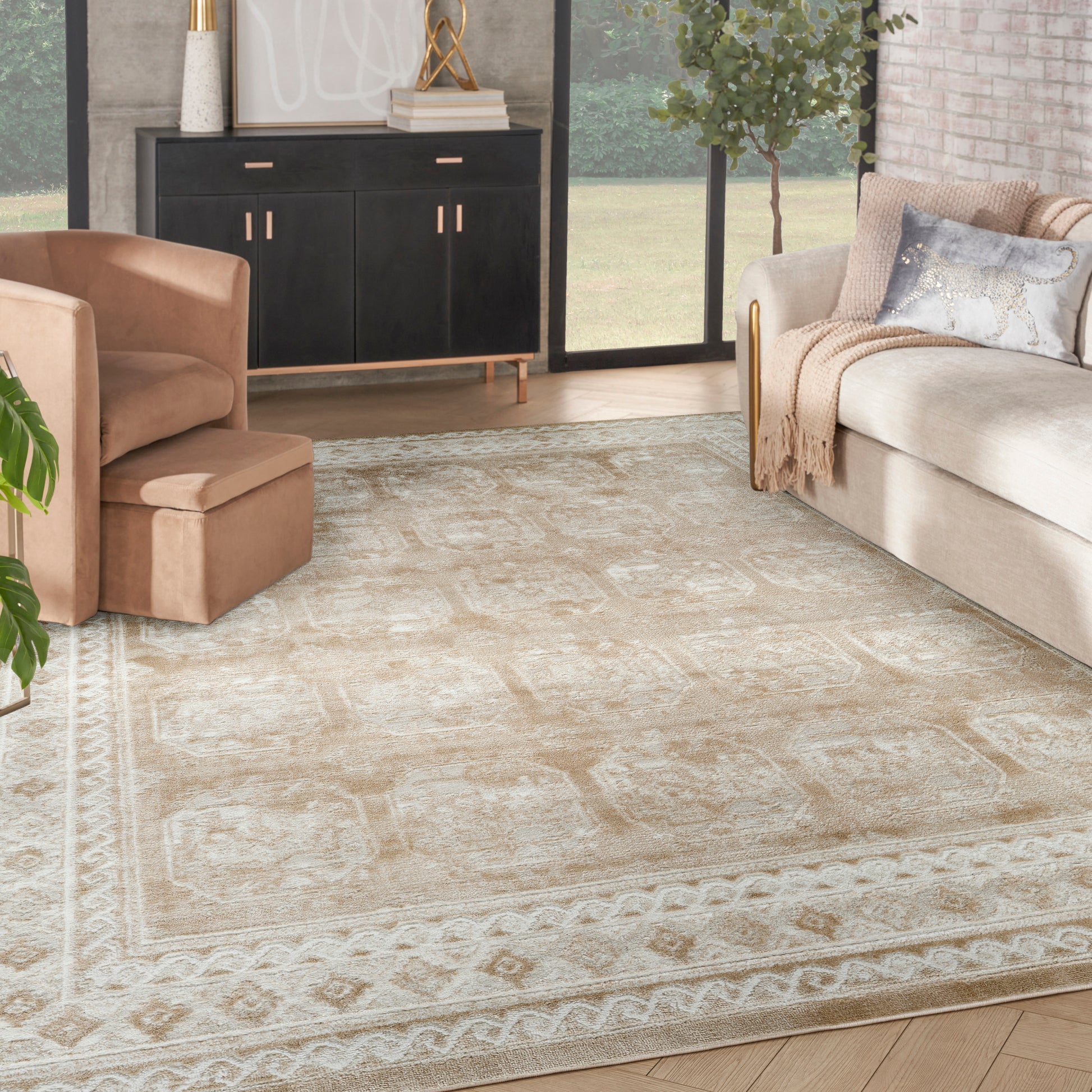 Beige patterned rectangular area rug in a modern living room with a tan armchair, cream sofa, and black sideboard.